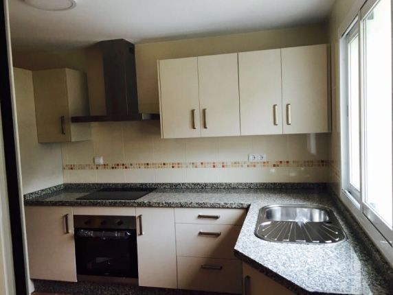 Una cocina con gabinetes blancos y encimeras de granito.