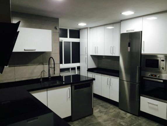 Una cocina con gabinetes blancos y electrodomésticos de acero inoxidable.