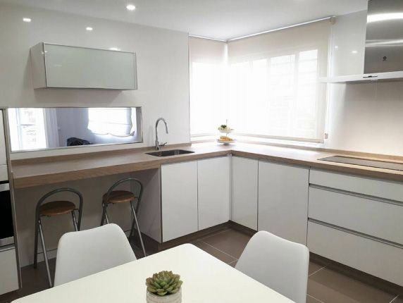 Una cocina con gabinetes blancos y una mesa con una planta encima.