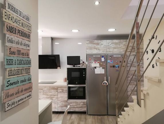Una cocina con un reloj en la pared encima de las escaleras.