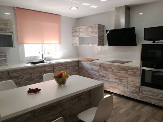 Una cocina con una mesa y sillas y un bol de fruta encima.