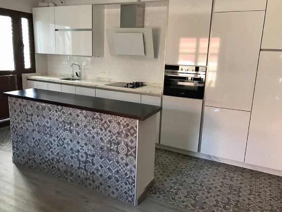 Una cocina con gabinetes blancos y una encimera negra.