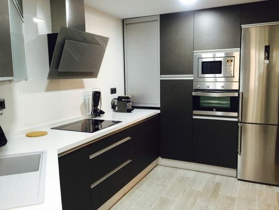 Una cocina con electrodomésticos de acero inoxidable y gabinetes negros.