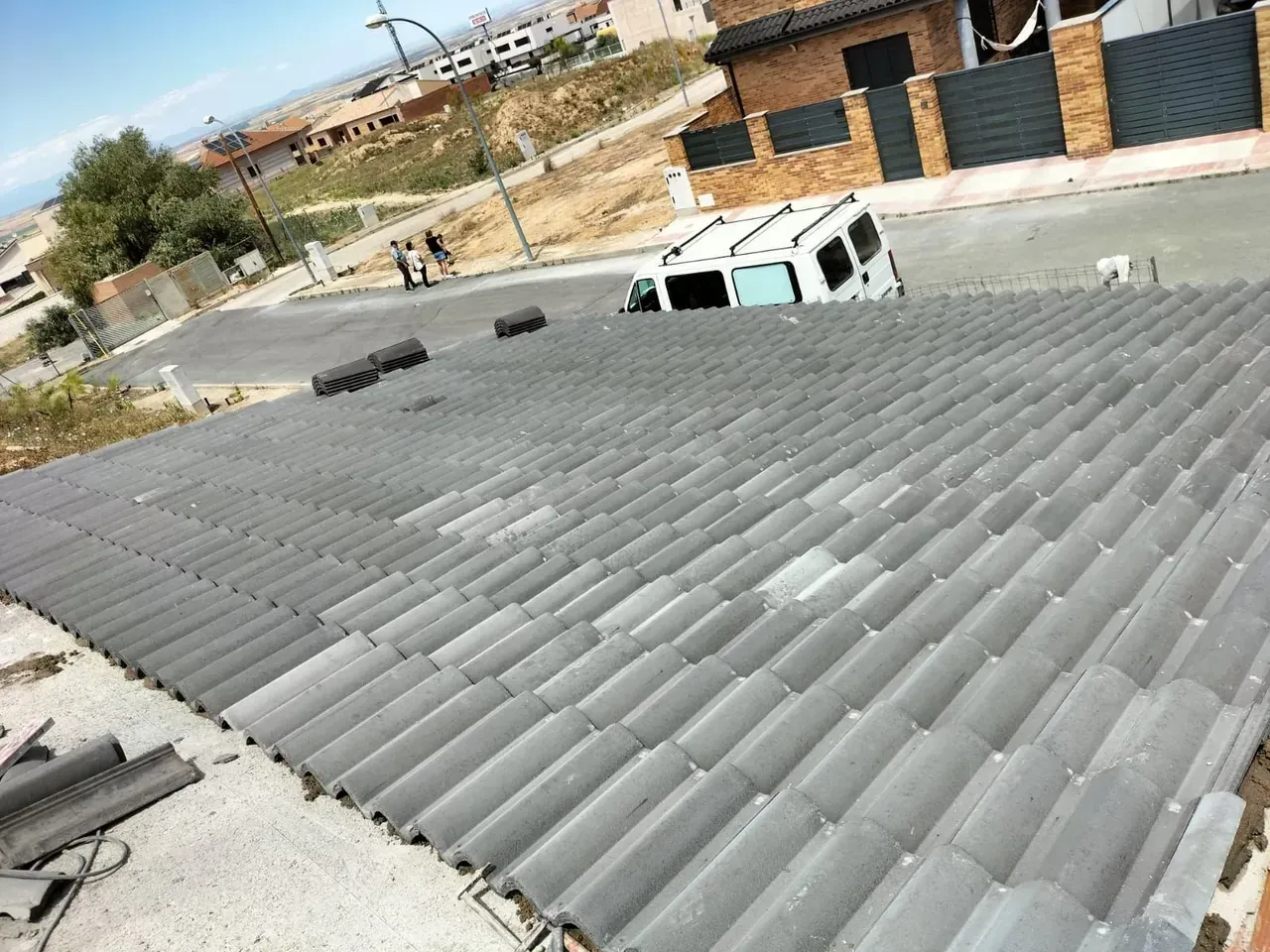 Tejado de tejas grises con una furgoneta blanca aparcada en la calle al fondo.