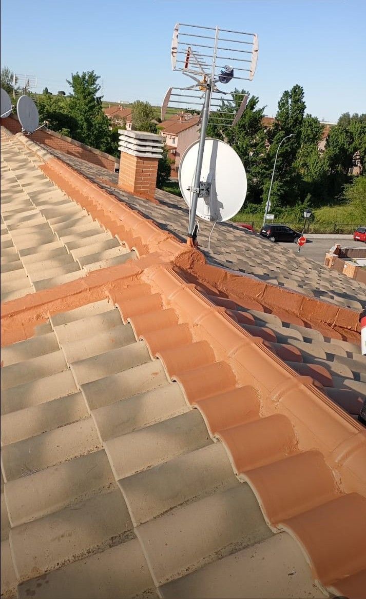 Azotea con tejas naranjas y grises, chimenea, antena de televisión y antena parabólica.