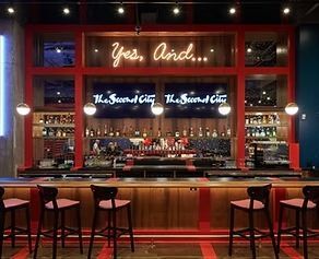 Bar inside Second City with red accents and neon sign: 