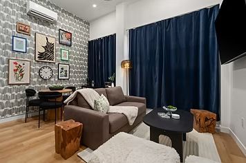 Living room with patterned wallpaper, sofa, dark curtains, and artwork.