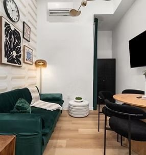 Cozy living space with green velvet sofa, art, and dining area.