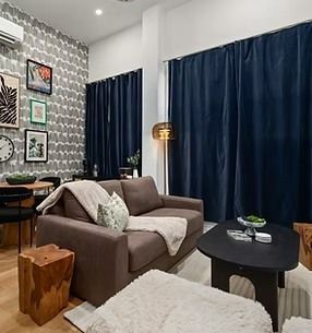 Living room with brown sofa, dark blue curtains, and artwork on a patterned wall.