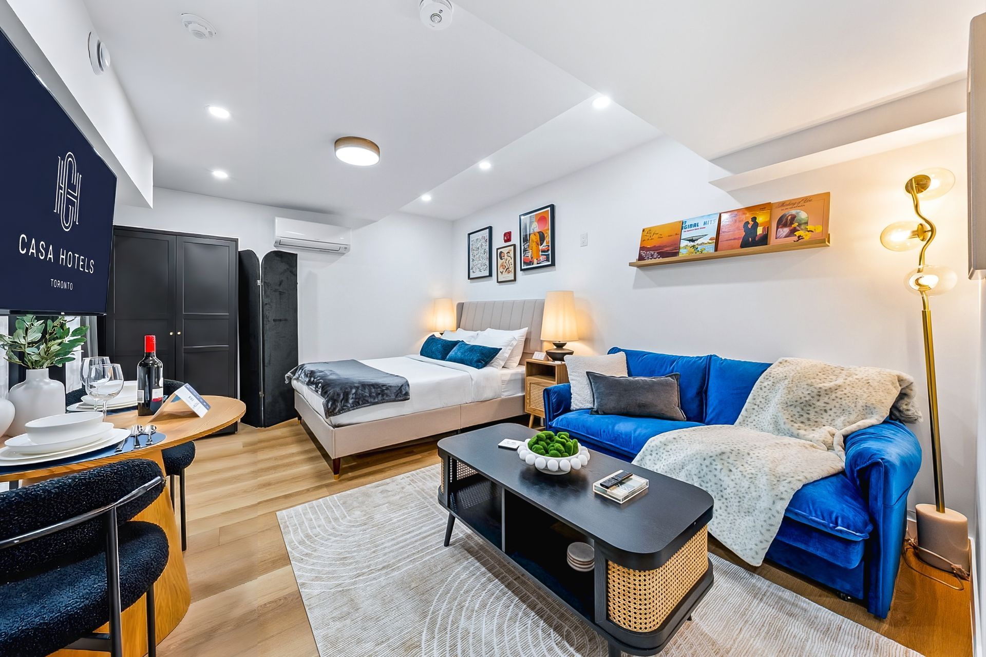 Bright studio apartment with blue sofa, bed, desk, and kitchenette in a compact modern layout