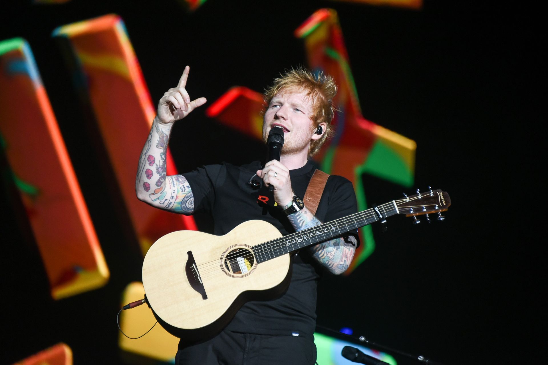 Ed Sheeran performing on stage during a concert.