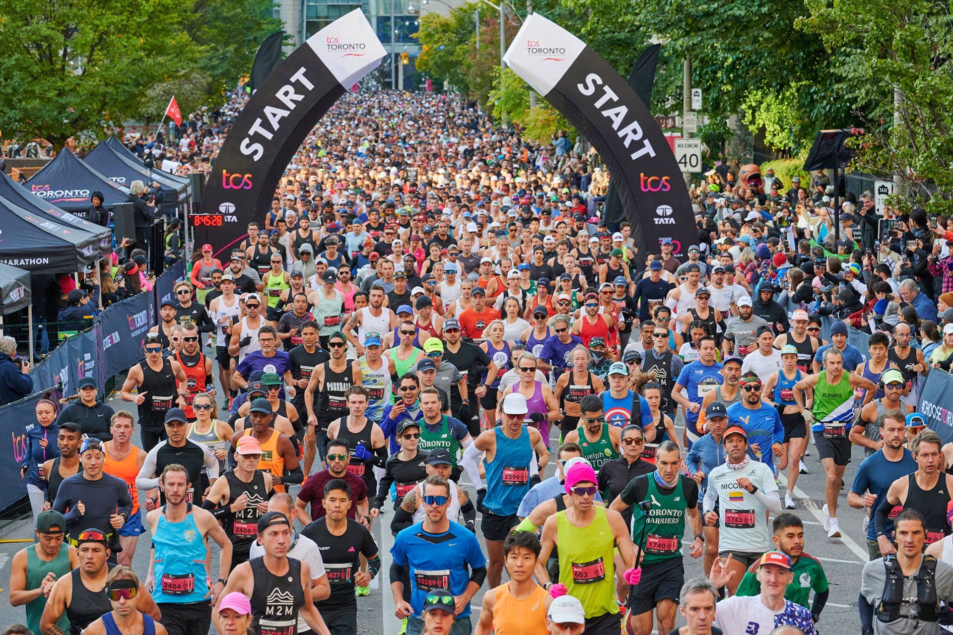 Crowd of runners at the start of the TCS Toronto Waterfront Marathon, with the START arch and Toronto.