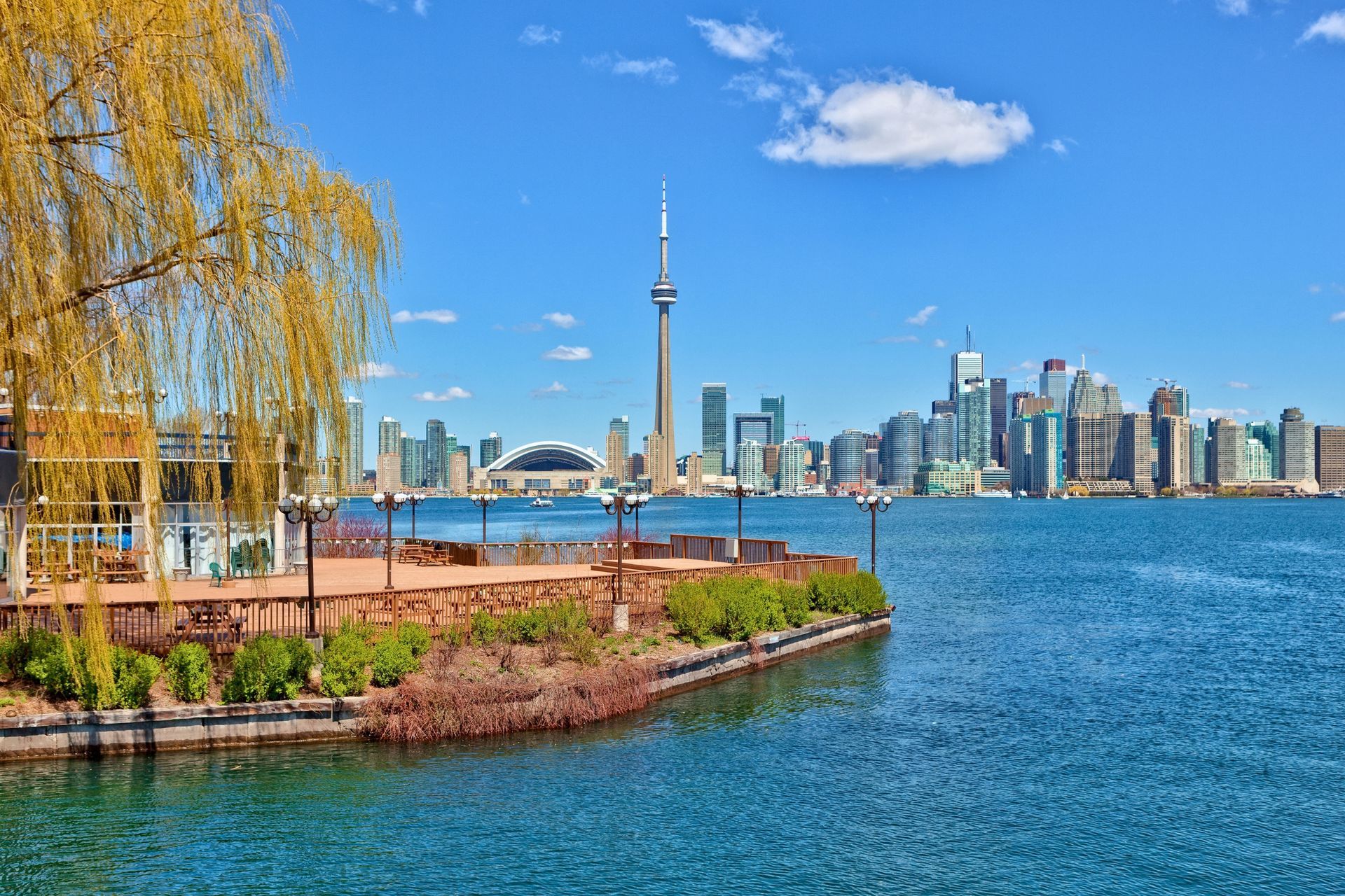 Toronto skyline with the CN Tower overlooking Lake Ontario and the waterfront on a clear blue-sky day.