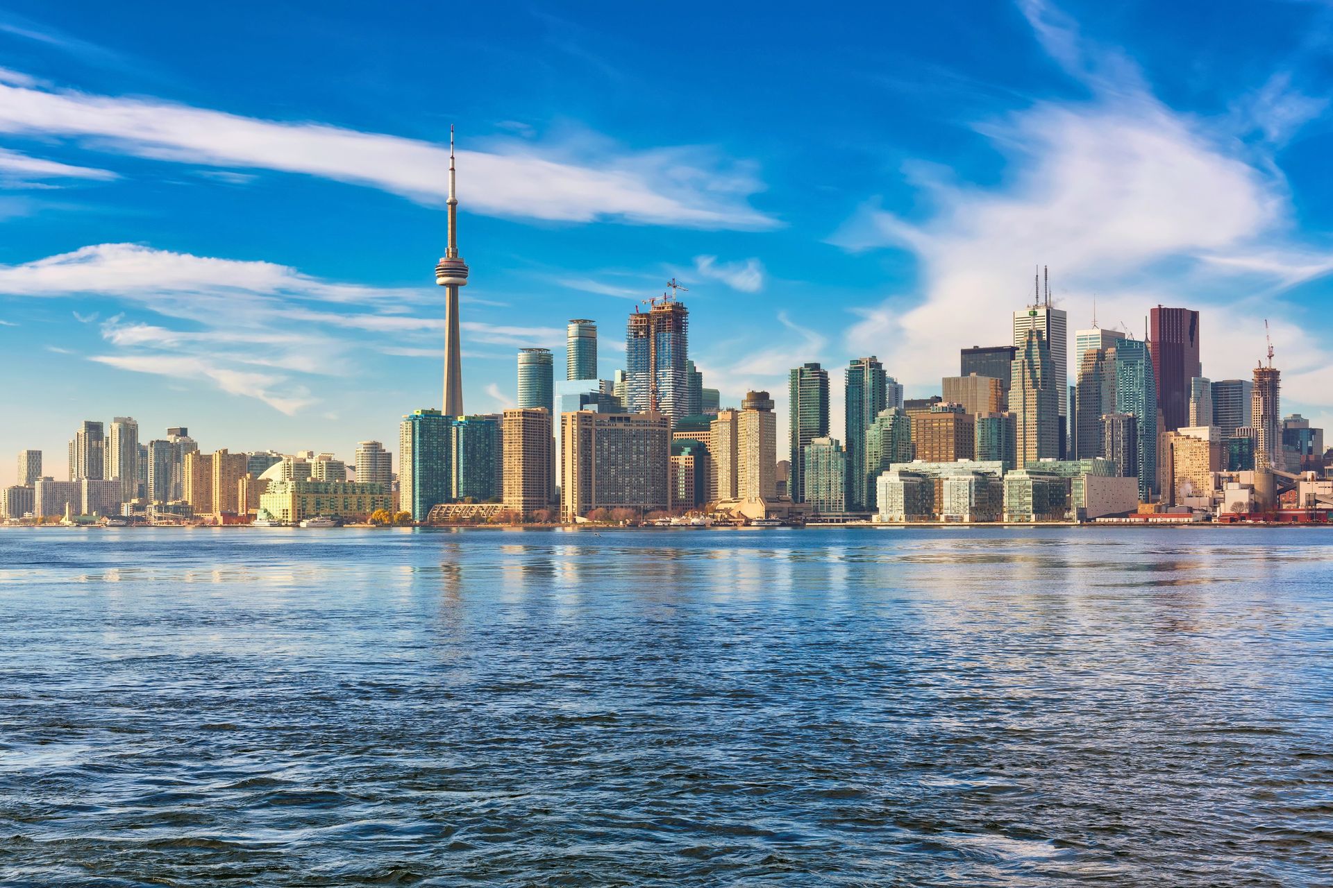 Toronto skyline on a clear day, with the CN Tower and downtown towers seen across the calm blue water of Lake Ontario