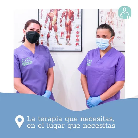 Dos mujeres que llevan mascarillas y uniformes médicos están paradas una al lado de la otra en una habitación.