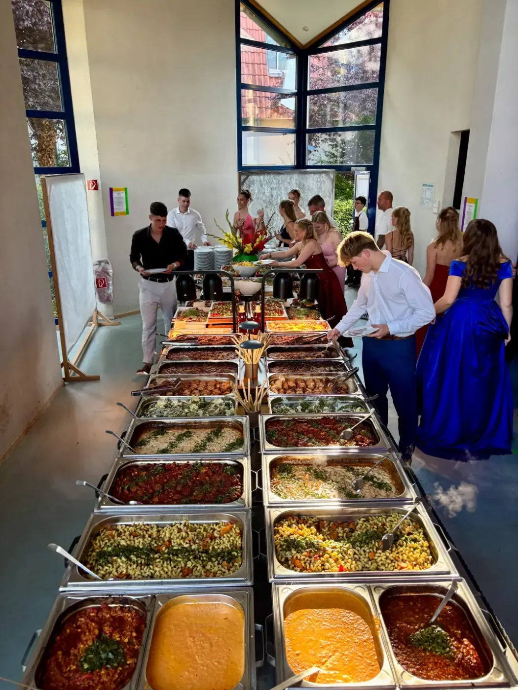 Eine Gruppe von Menschen steht um einen Buffettisch herum, der mit viel Essen gefüllt ist.