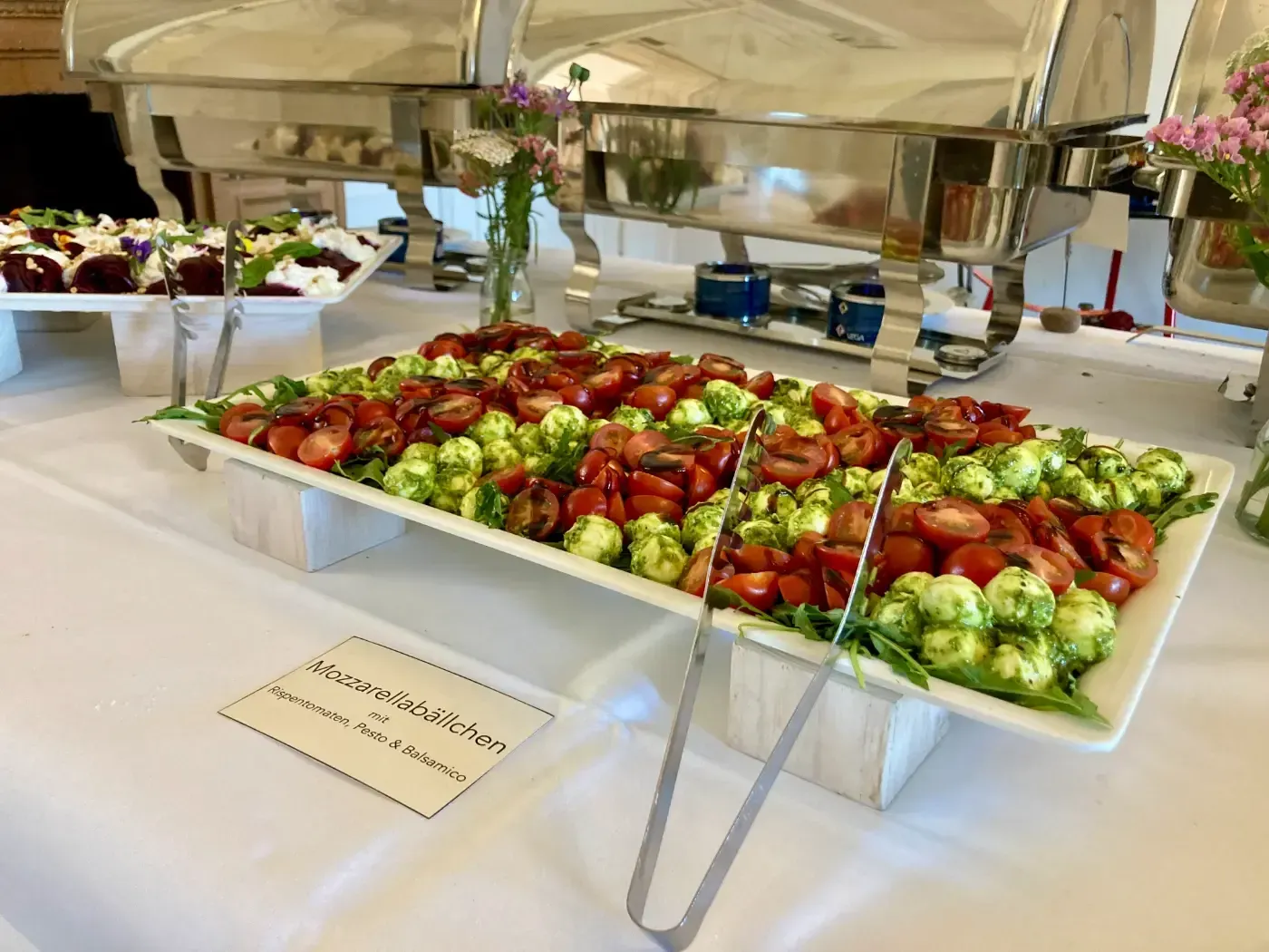 Ein Buffet-Tisch mit Tellern voller Essen und Zangen darauf.