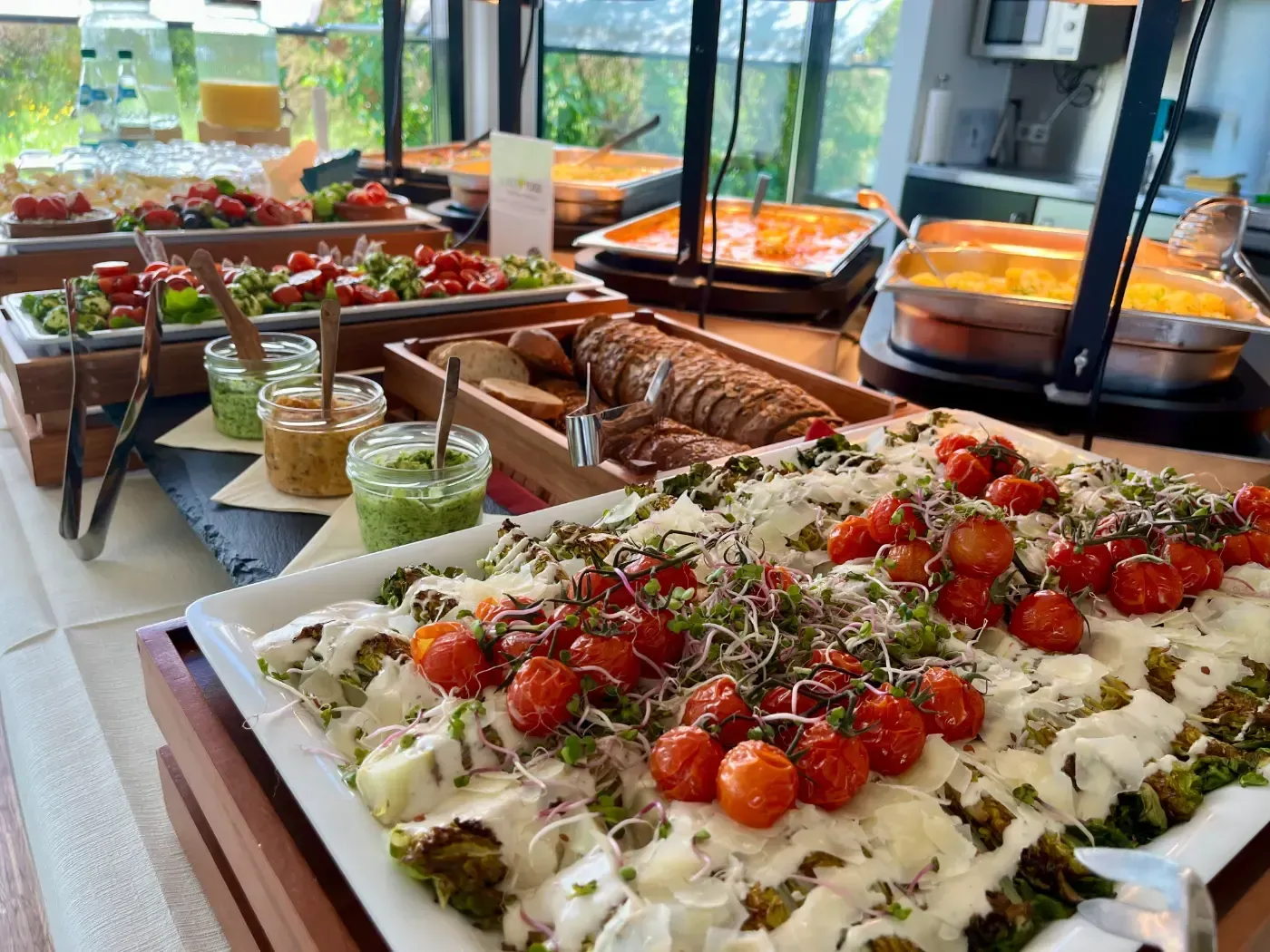 Ein Buffettisch voller Speisen, darunter auch eine Pizza mit Tomaten darauf.