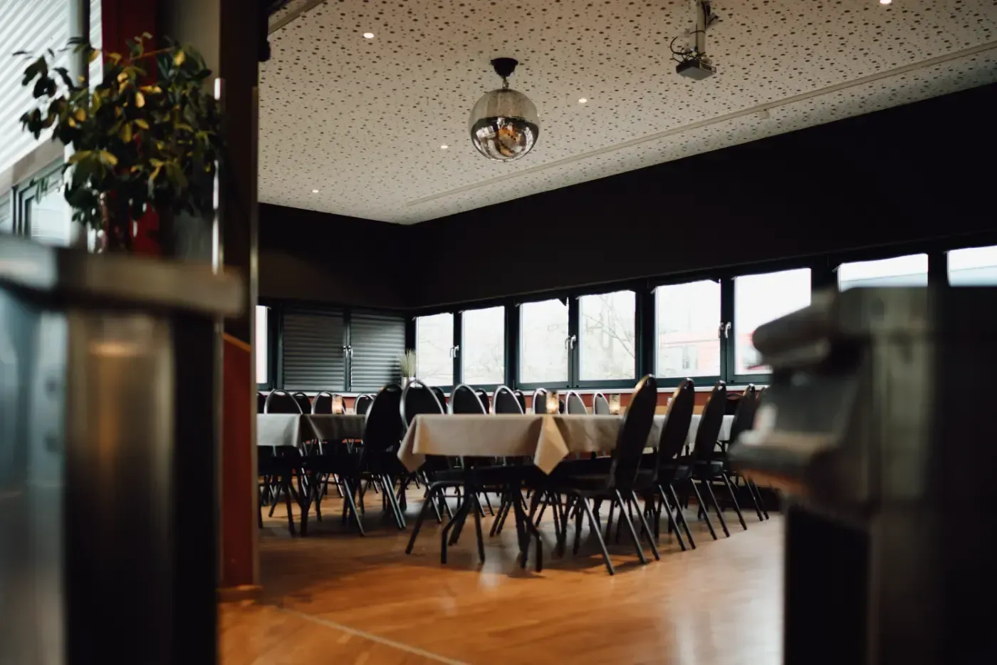 Ein Esszimmer mit Tischen und Stühlen und einer Discokugel, die von der Decke hängt.