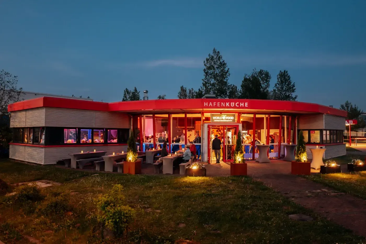 Ein Restaurant, in dem abends Leute draußen an Tischen sitzen.