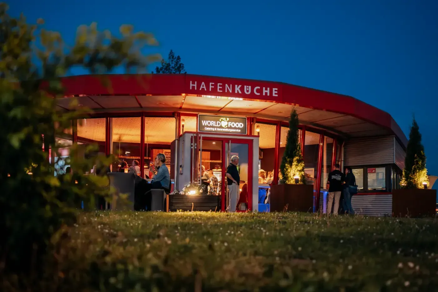 Eine Gruppe von Menschen steht nachts vor einem Restaurant.