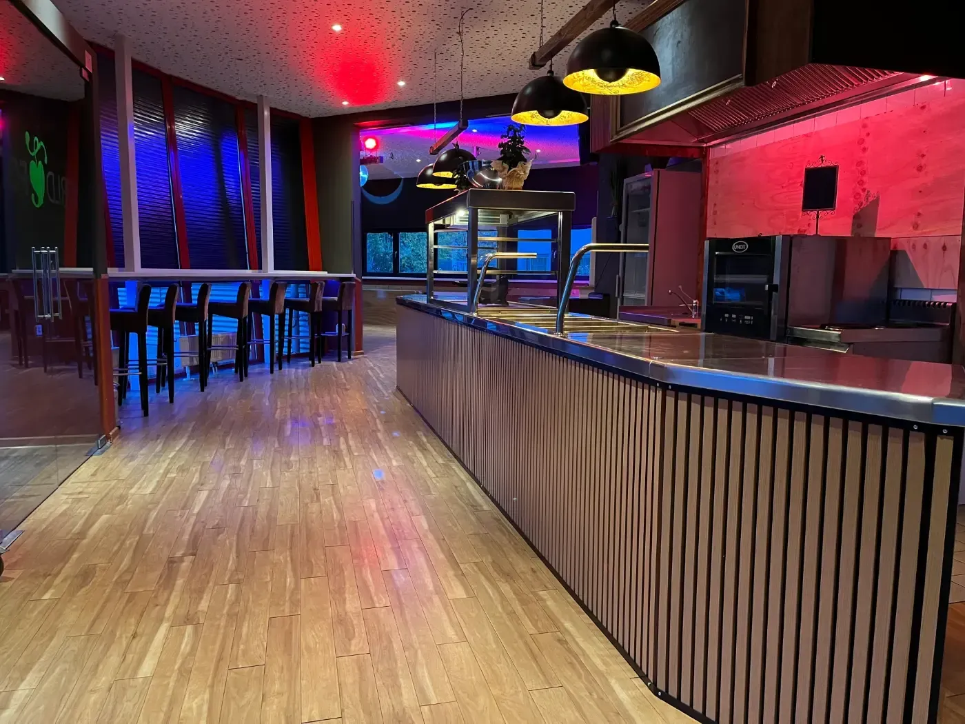 Eine lange Holztheke in einem Restaurant mit Tischen und Stühlen.