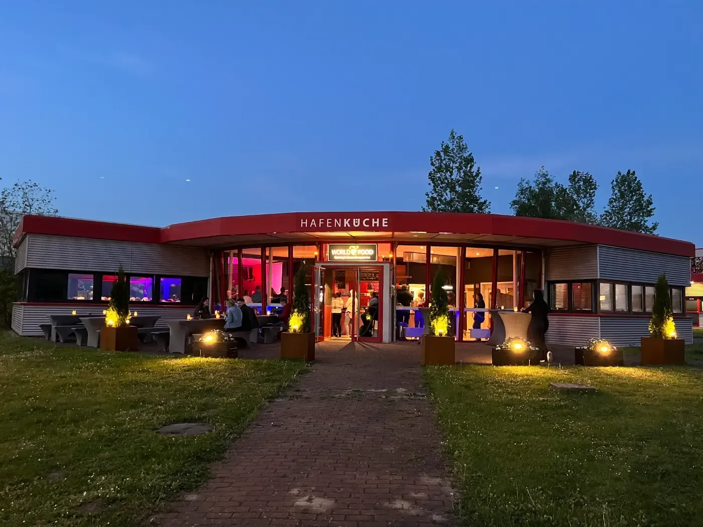 Ein Restaurant mit einer roten Markise ist nachts beleuchtet.