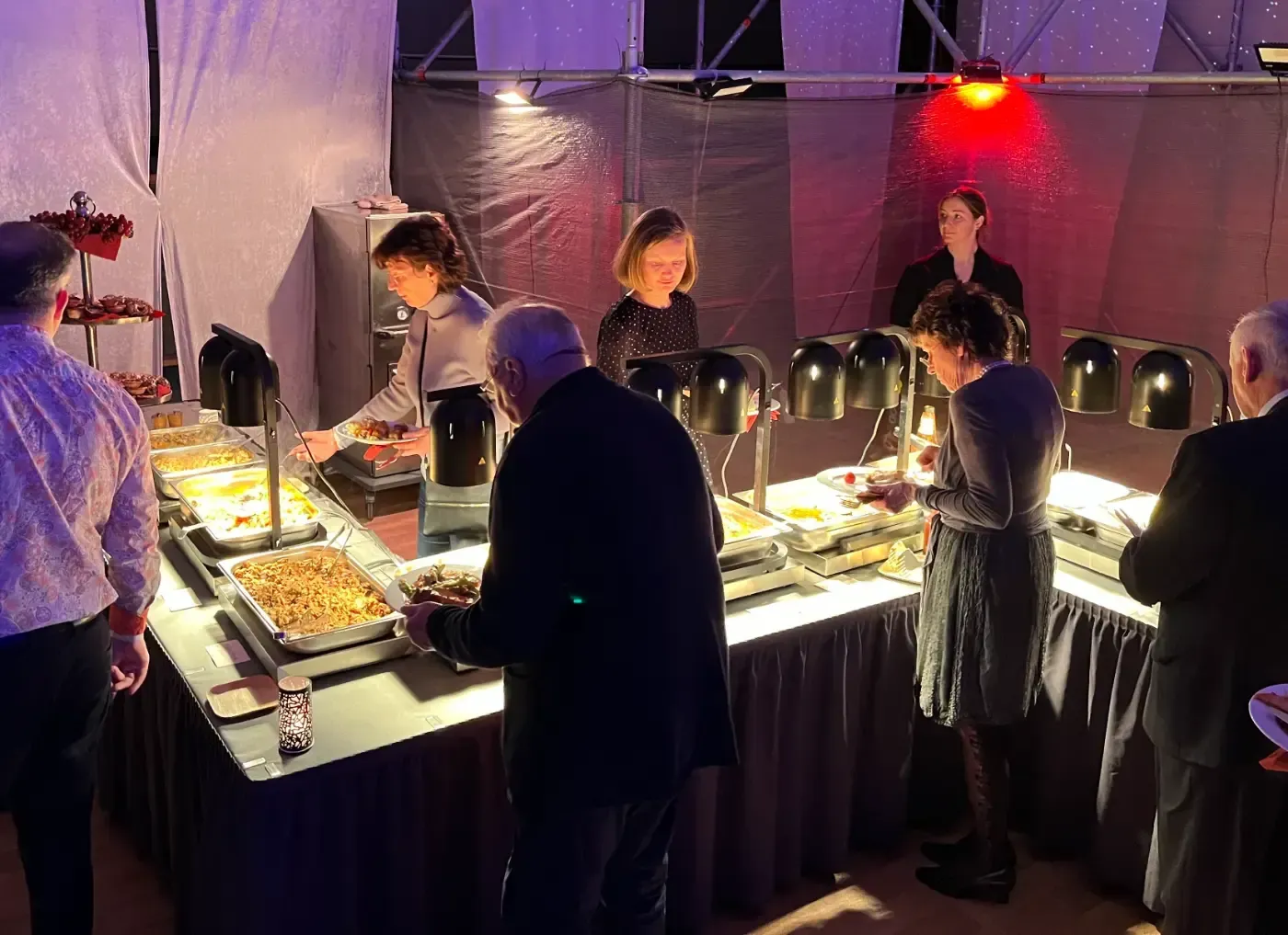 Eine Gruppe von Menschen steht um einen Buffettisch herum.