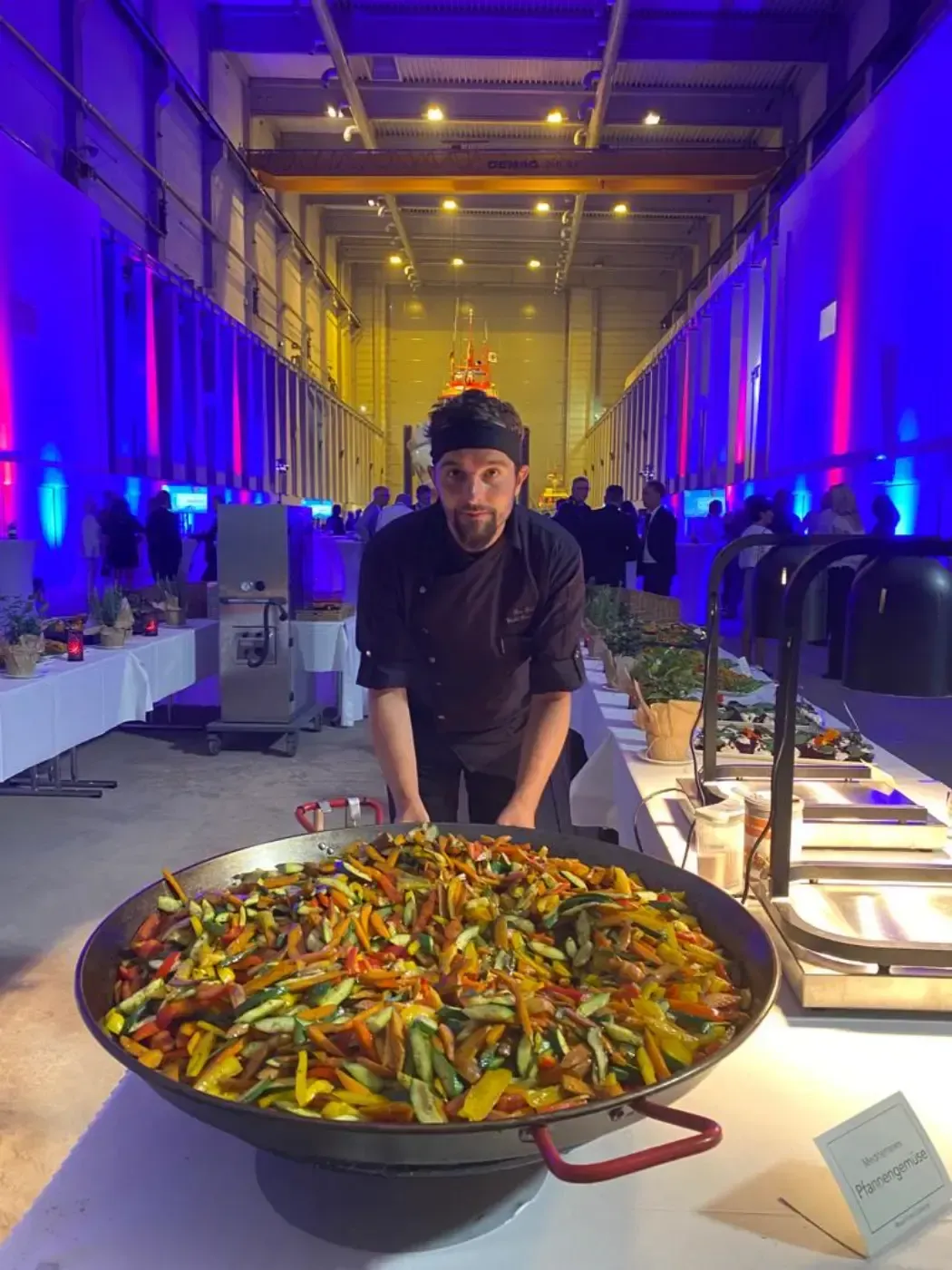 Ein Mann steht vor einer großen Pfanne mit Essen.