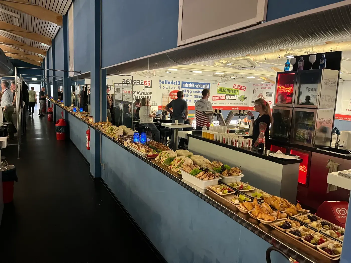 Eine lange Schlange am Buffet in einem Restaurant, hinter der Menschen stehen.