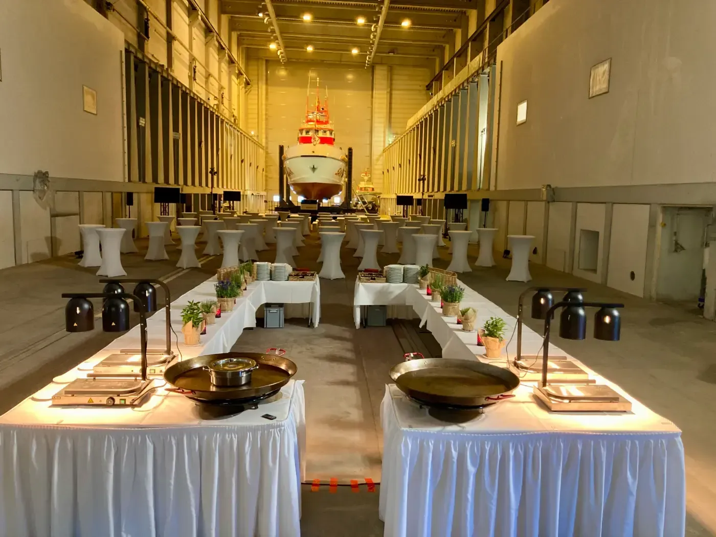 Ein großer Raum mit Tischen und einem Boot im Hintergrund.