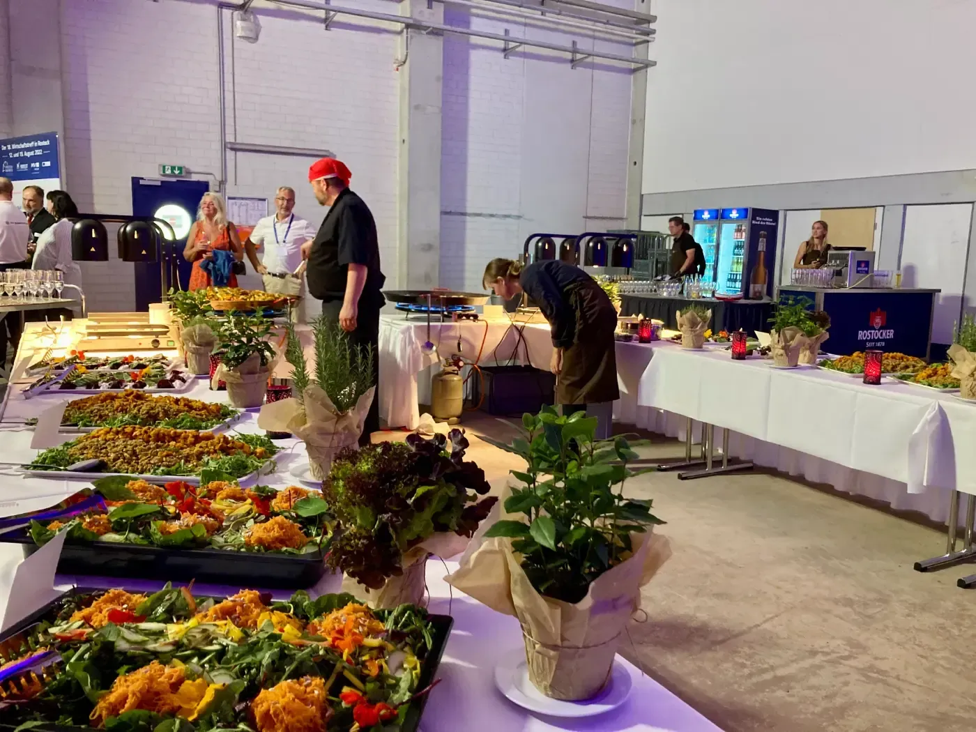 Eine Gruppe von Menschen steht um einen mit Essen gefüllten Buffettisch herum.