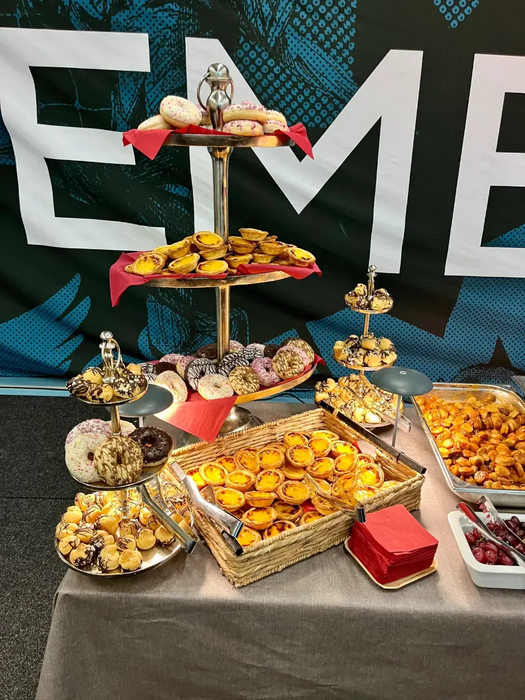 Ein Tisch mit einer Menge Essen darauf vor einem Schild mit der Aufschrift „eme“