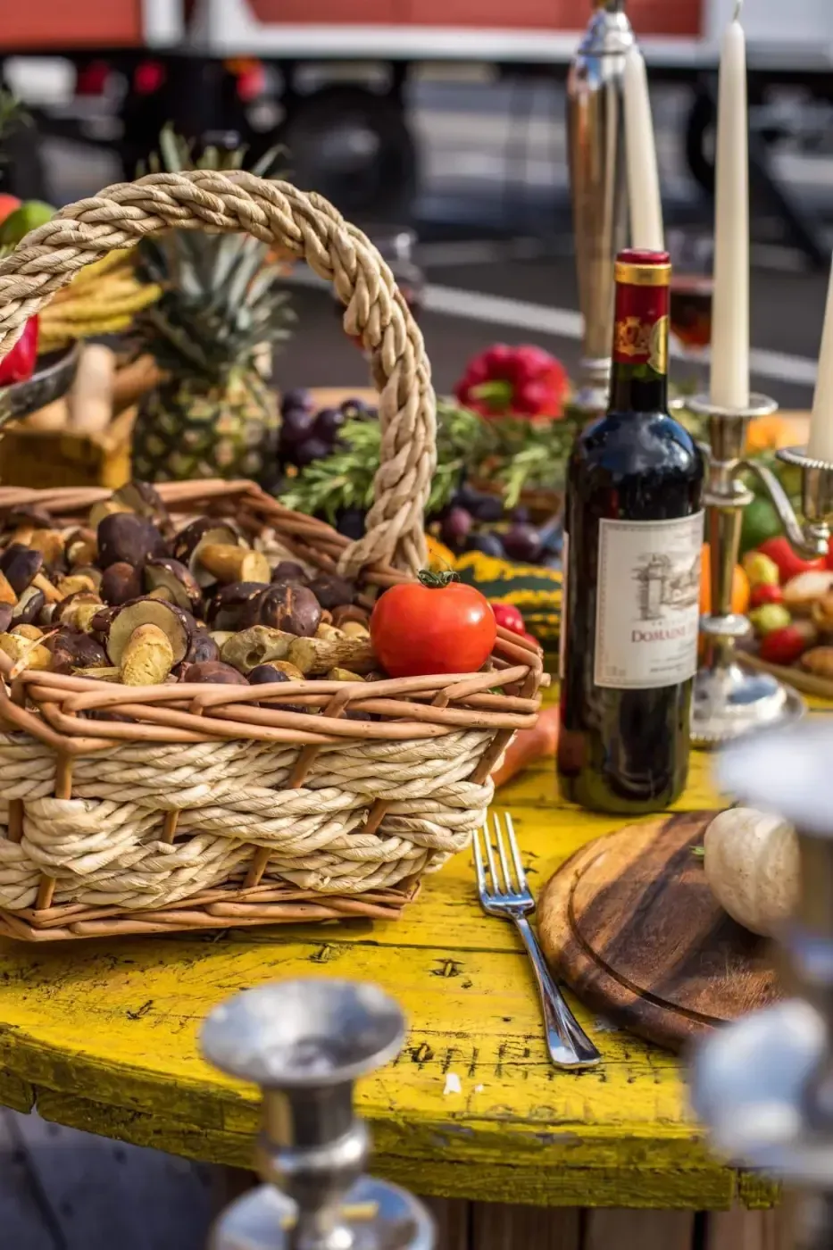 Auf einem Tisch steht eine Flasche Wein neben einem Korb mit Essen.