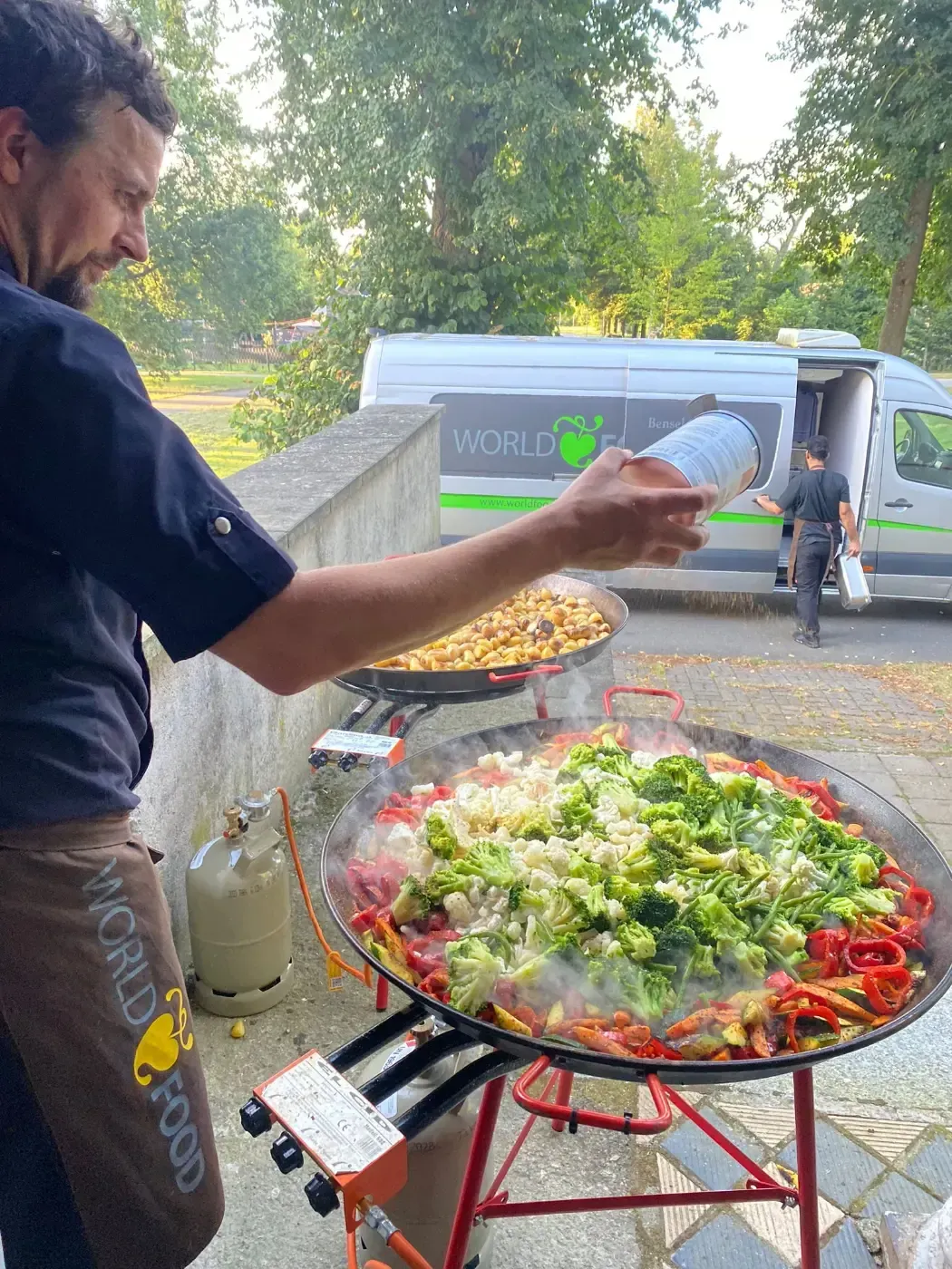 Ein Mann gießt Wasser in einen großen Topf mit Essen.