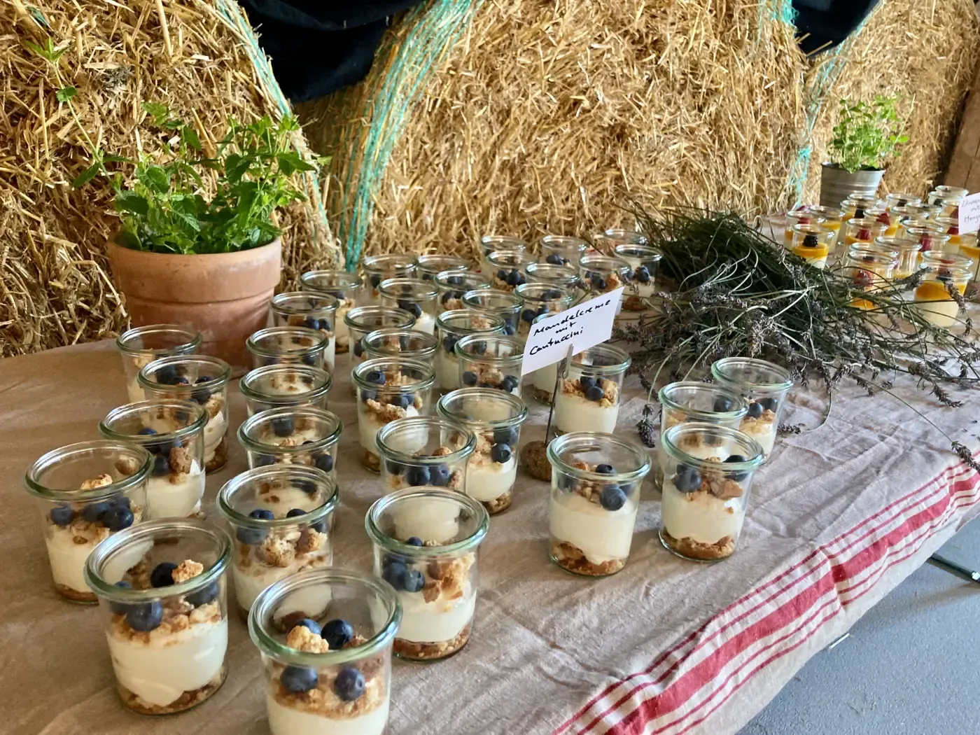 Ein Tisch mit Gläsern voller Desserts und Heuballen.