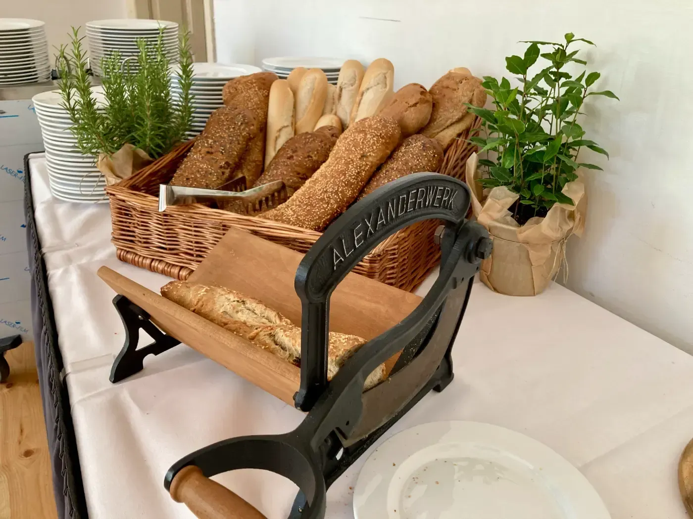 Auf einem Tisch steht neben einem Korb mit Brot eine Brotschneidemaschine.