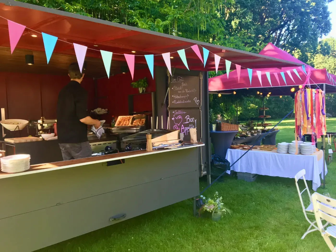 Ein Mann bereitet an einem Imbisswagen in einem Park Essen zu.