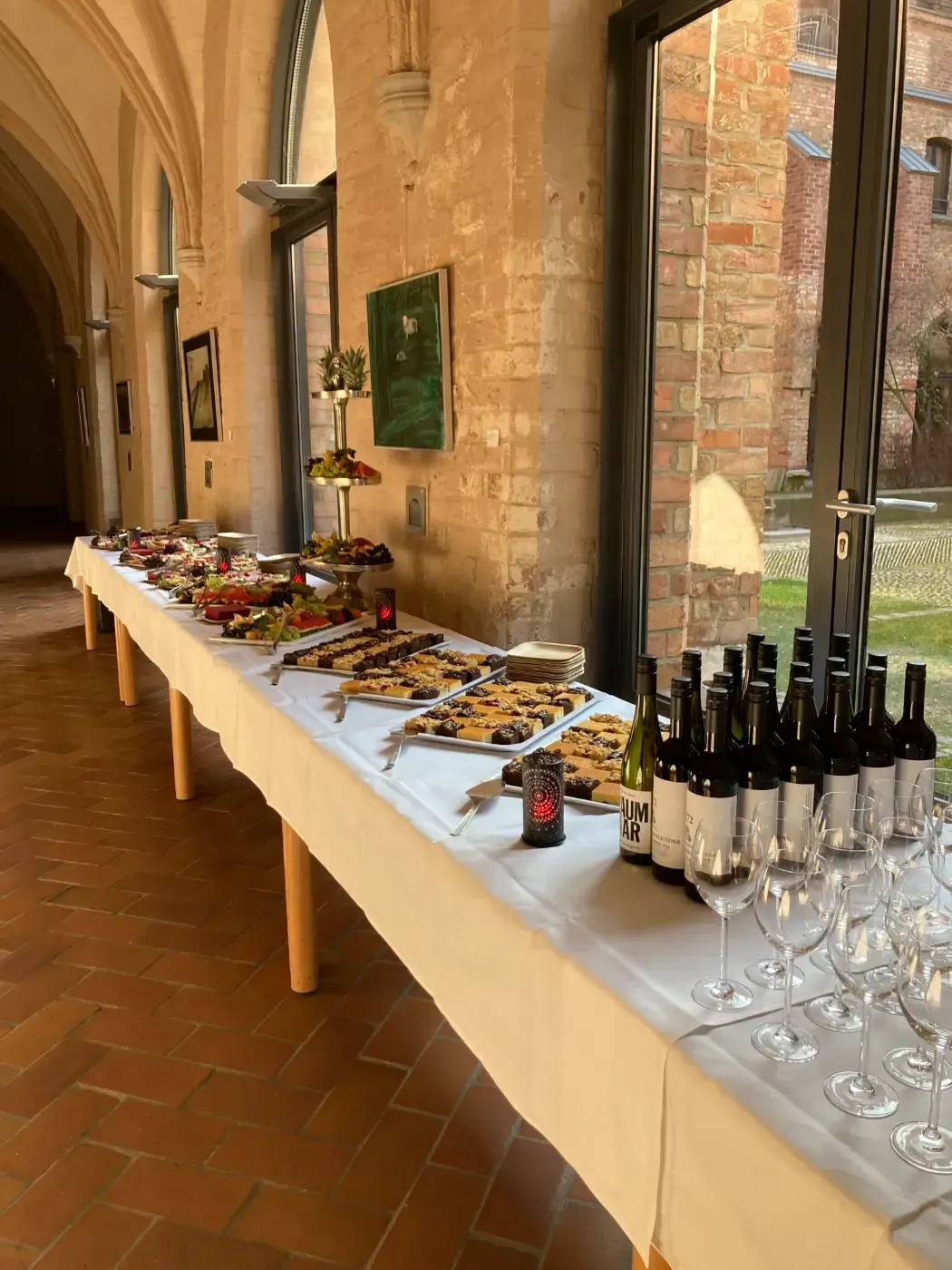 Ein langer Tisch mit Weinflaschen und Gläsern darauf.