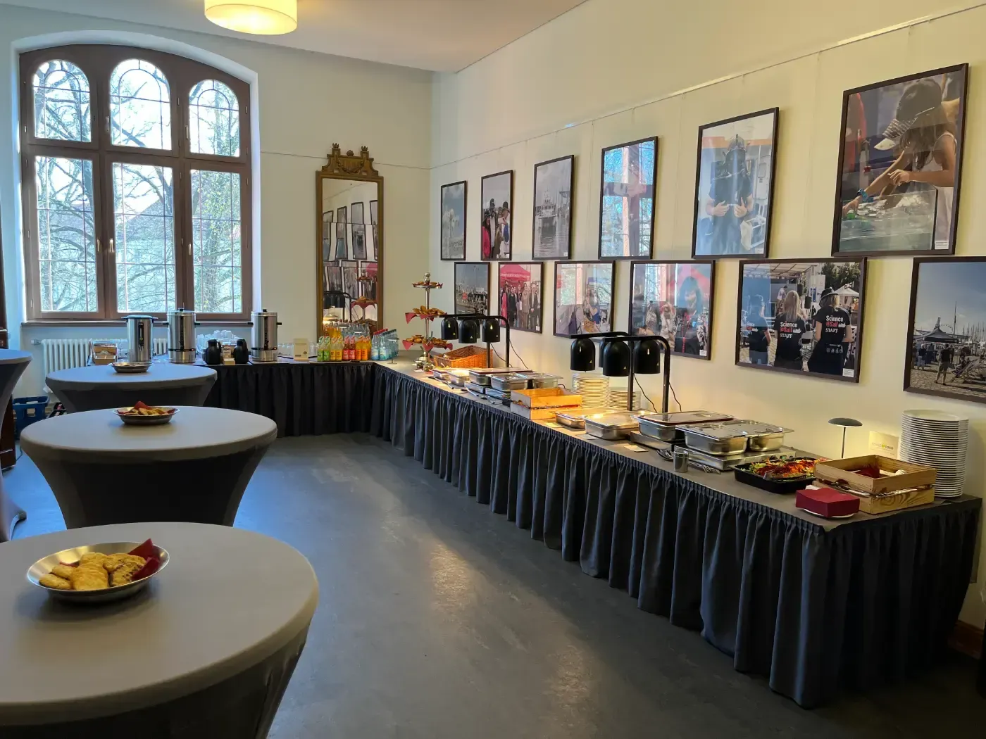 Ein Raum mit Tischen und einem langen Buffettisch mit Bildern an der Wand.