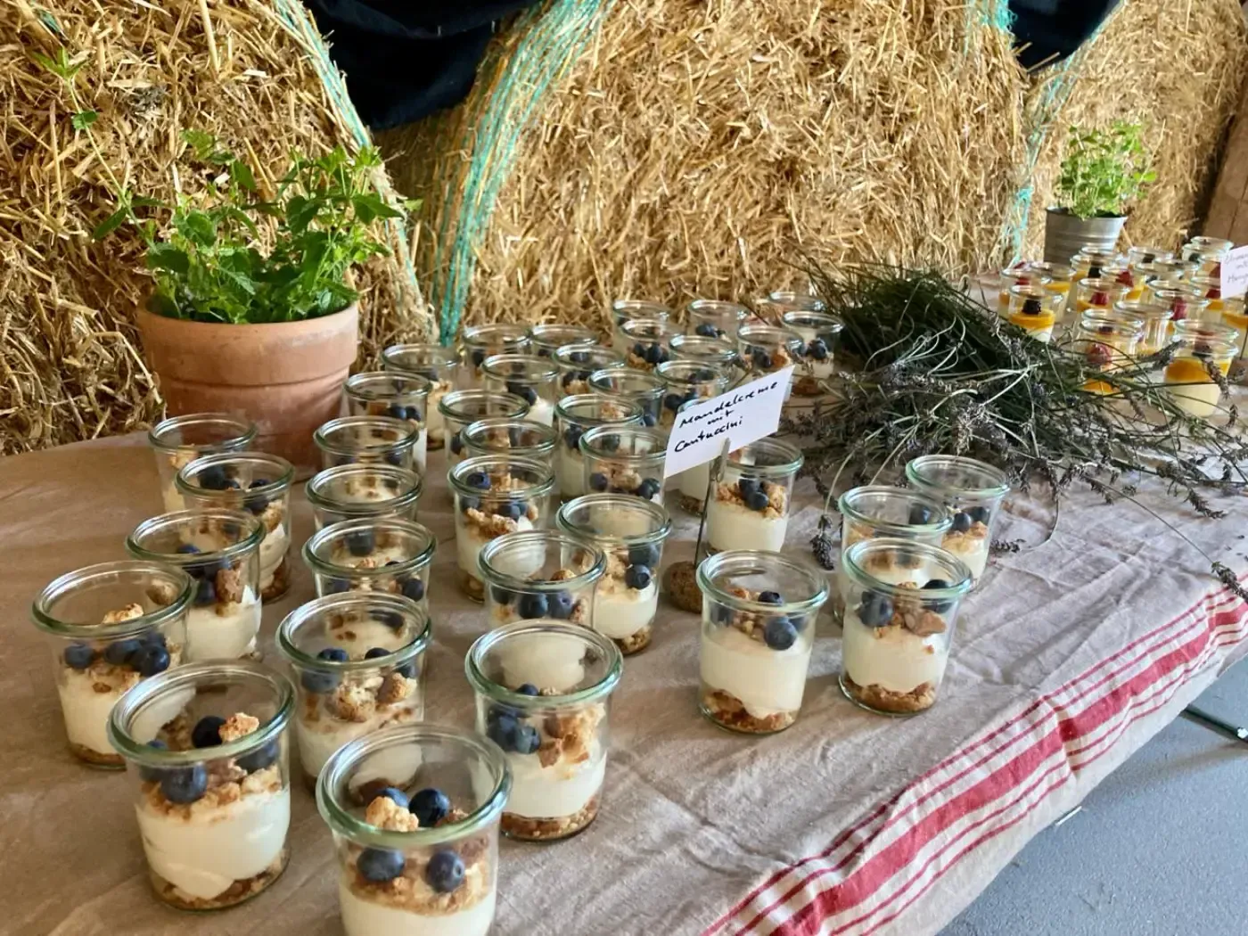 Ein Tisch mit Gläsern voller Desserts und Heuballen.