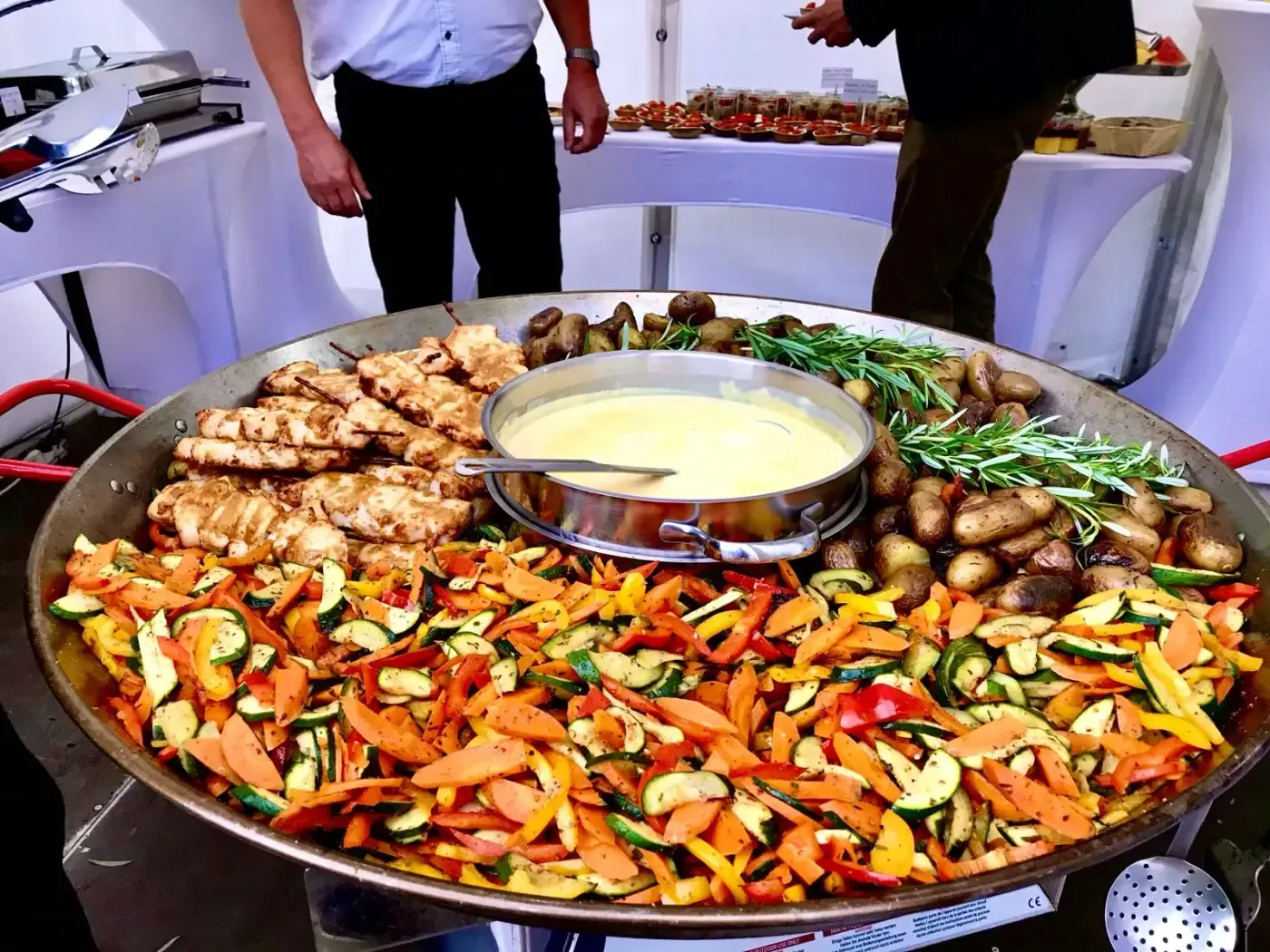 Auf einem Tisch steht eine große Pfanne mit Gemüse und Fleisch.