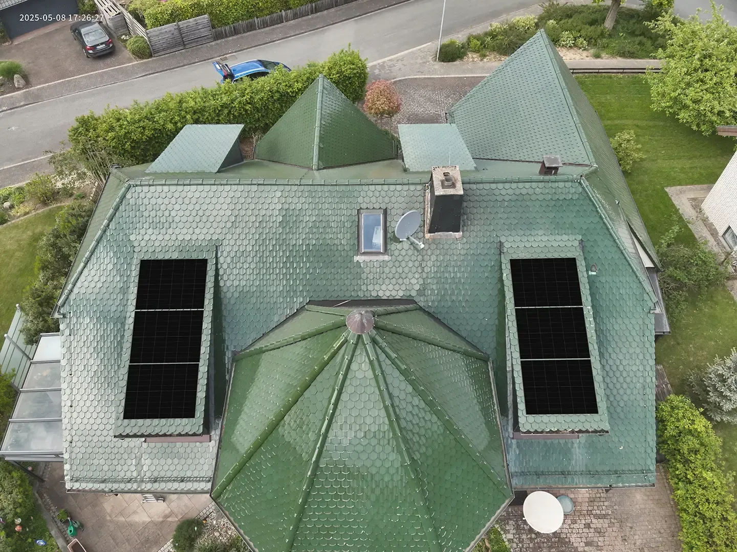 Draufsicht auf ein Haus mit Gründach, Solarpaneelen und Klimaanlage.