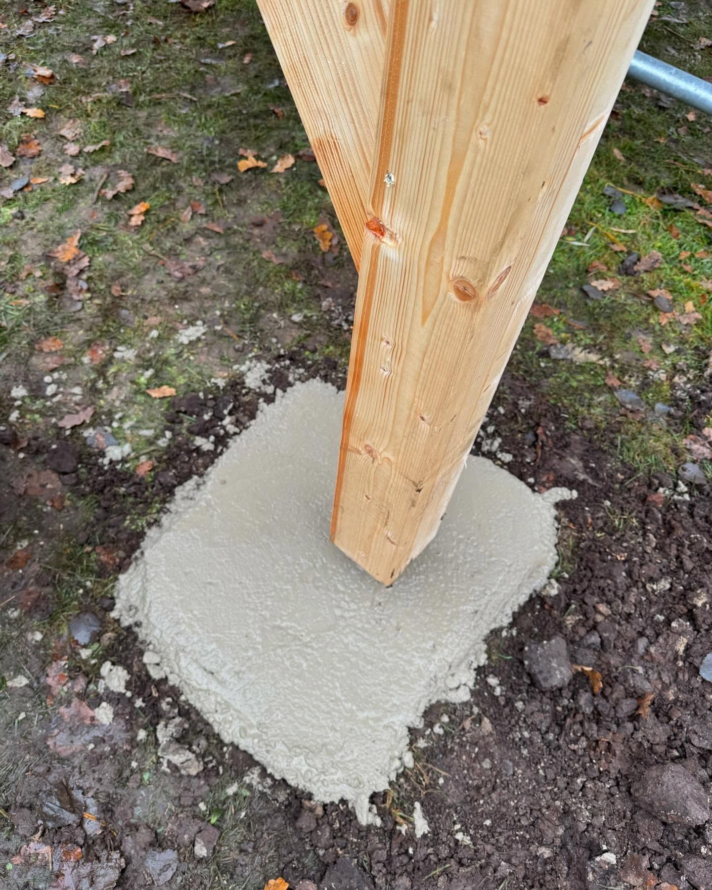 Auf einem Betonsockel steht ein Holzpfosten.