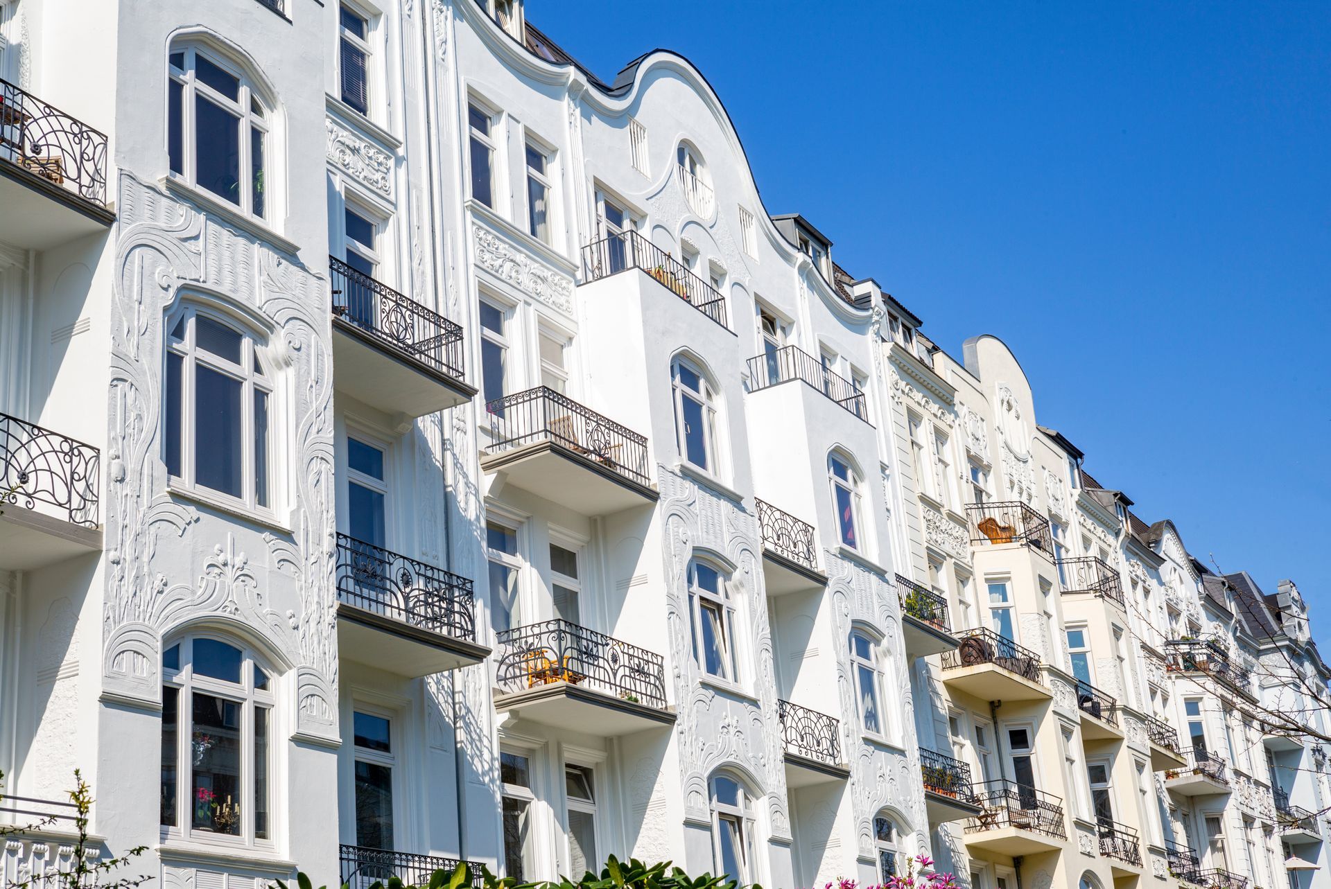 Eine Reihe weißer Wohnhäuser mit Balkonen an einem sonnigen Tag.