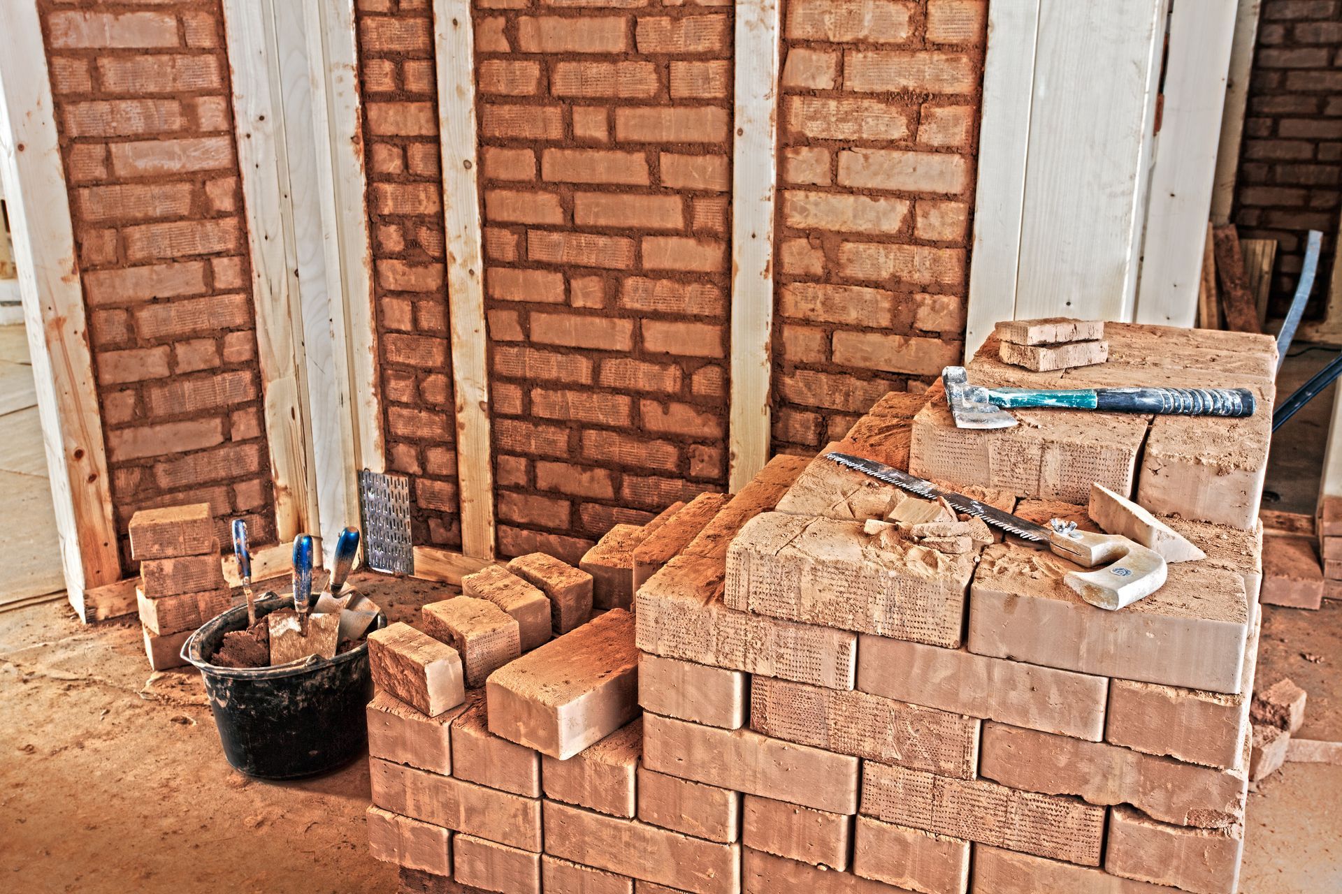 Mit Ziegeln und Werkzeug wird eine Ziegelmauer gebaut.