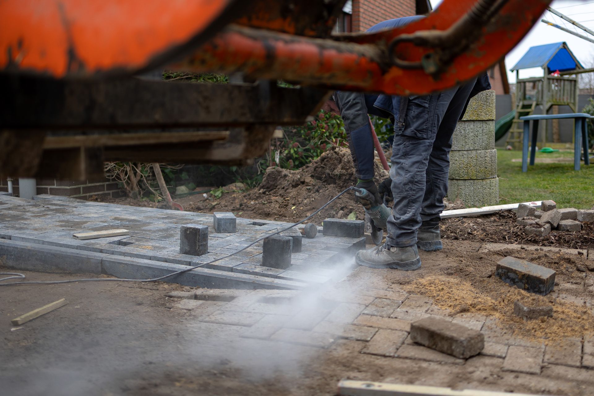 Eine Gruppe Bauarbeiter arbeitet an einem gemauerten Gehweg.