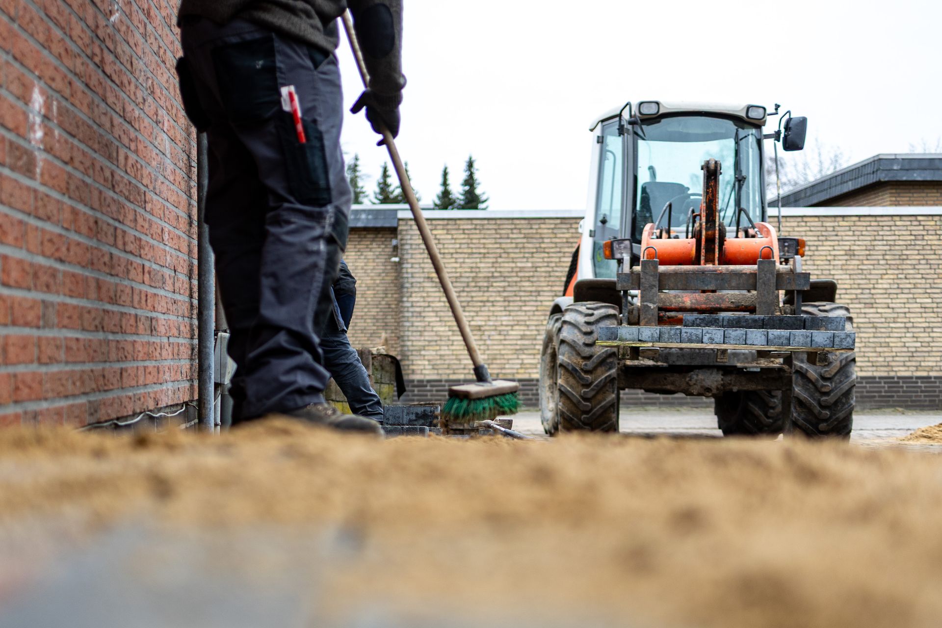 Ein Mann fegt den Boden vor einem Traktor.
