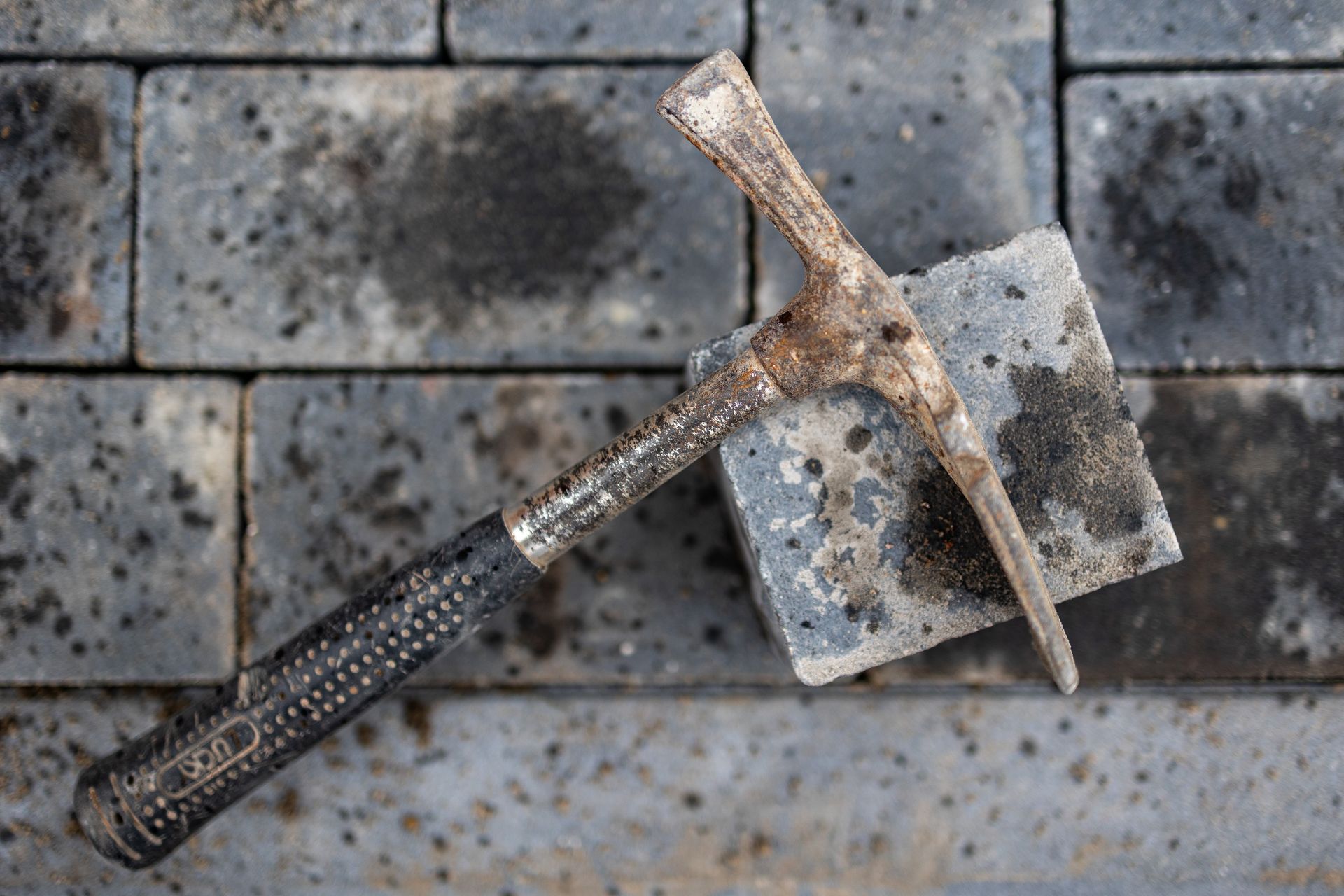 Ein Hammer und eine Schaufel liegen auf einer Ziegelmauer.