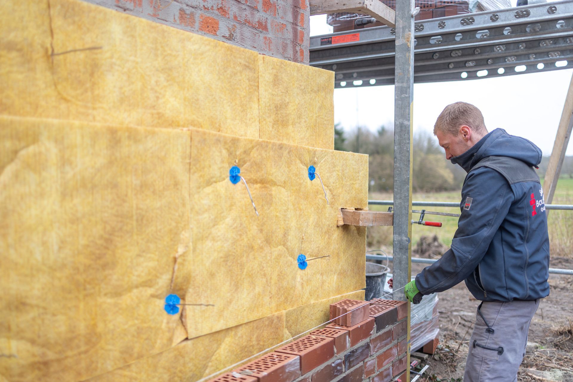Ein Mann bringt eine Isolierung an einer Ziegelwand an.